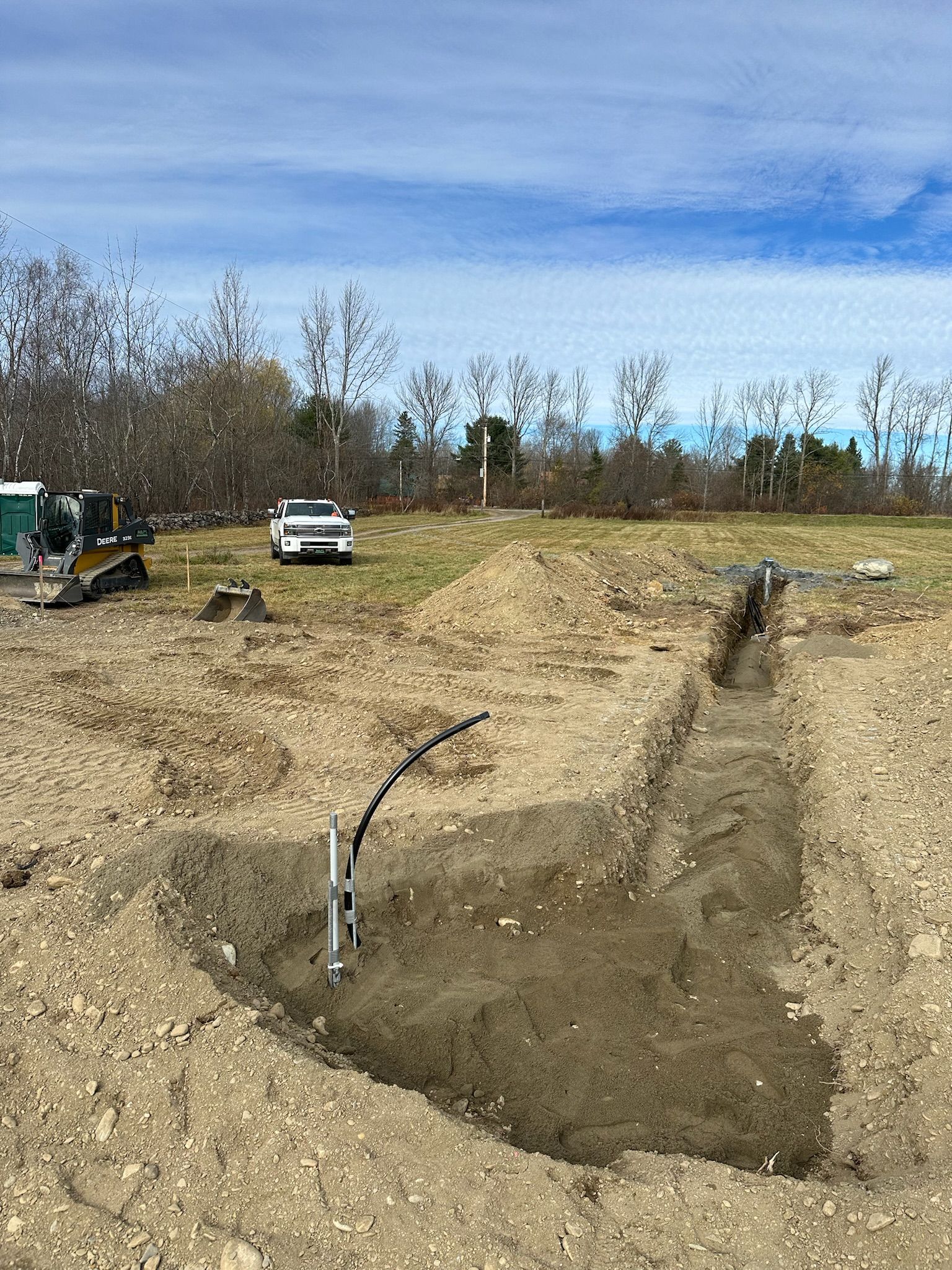 A car is parked in the middle of a dirt field.