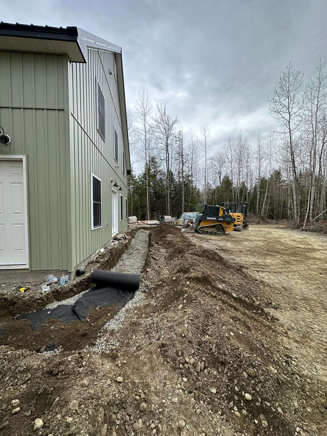 A large building is being built next to a dirt road.