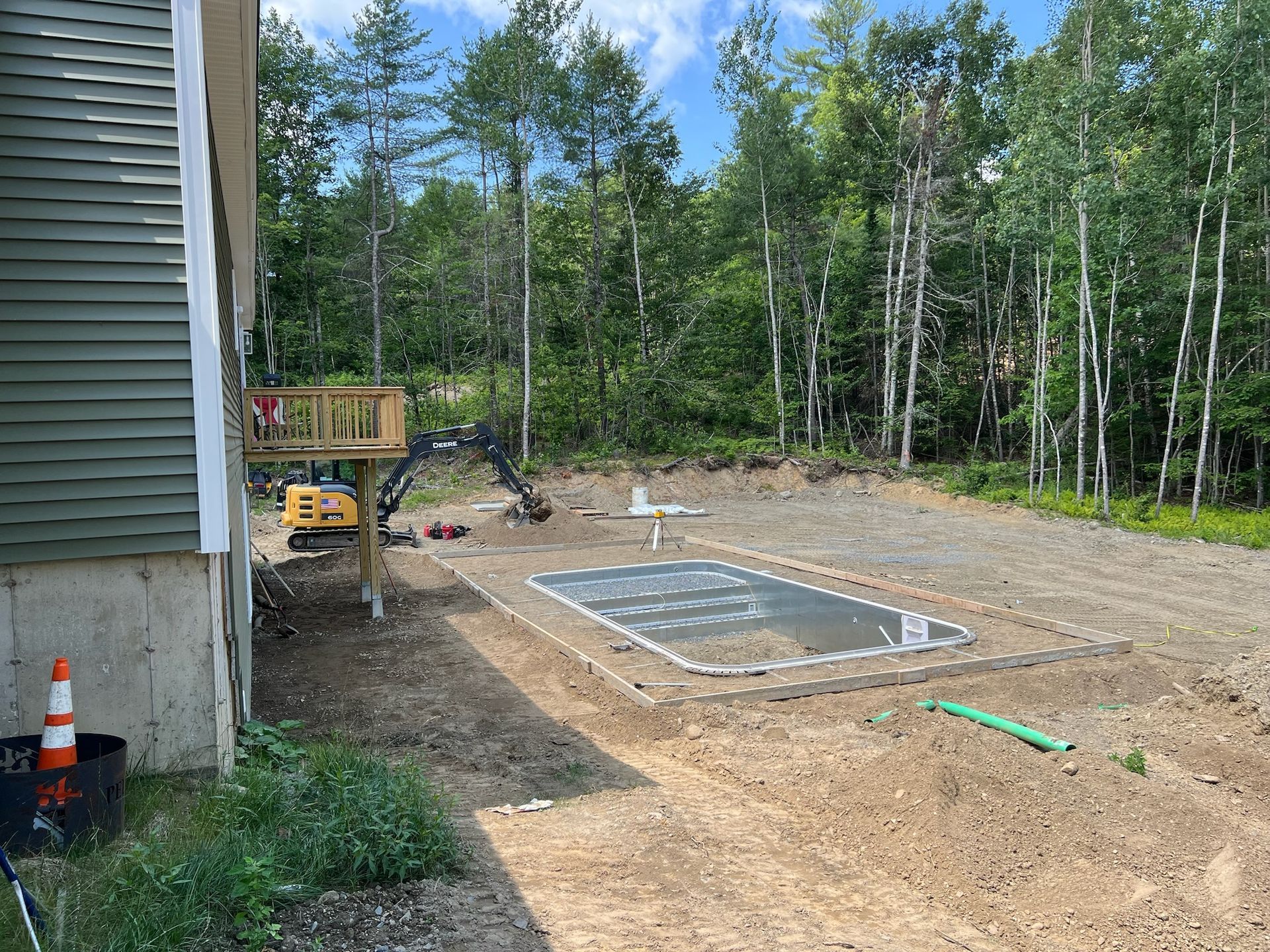 A house is being built in the middle of a dirt field with trees in the background.