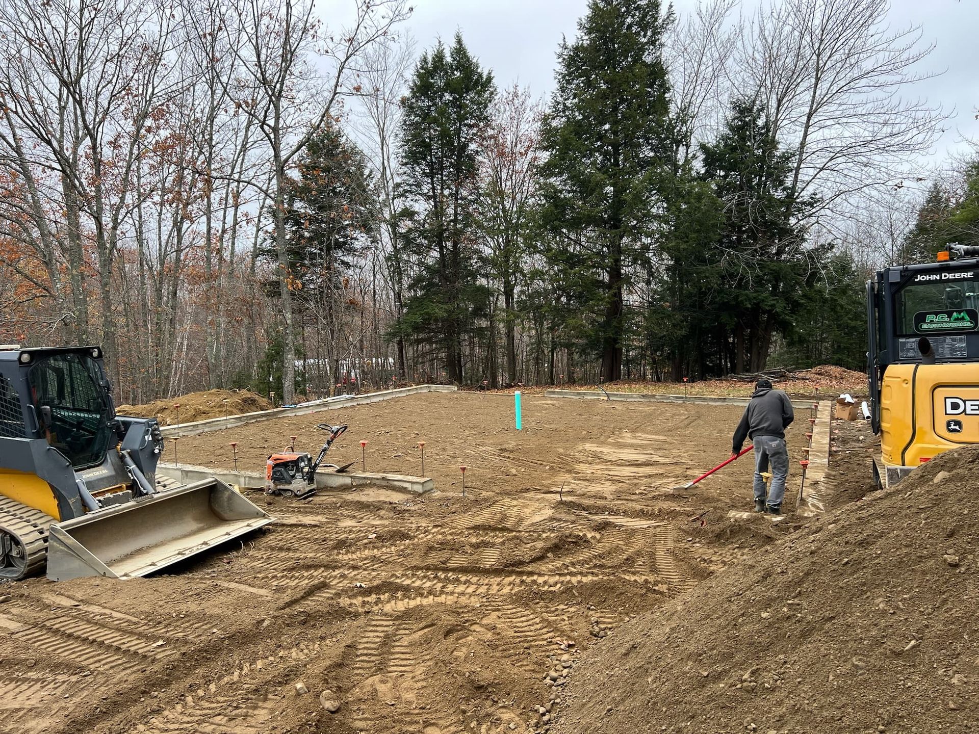 A man is standing next to a bulldozer in a dirt field.
