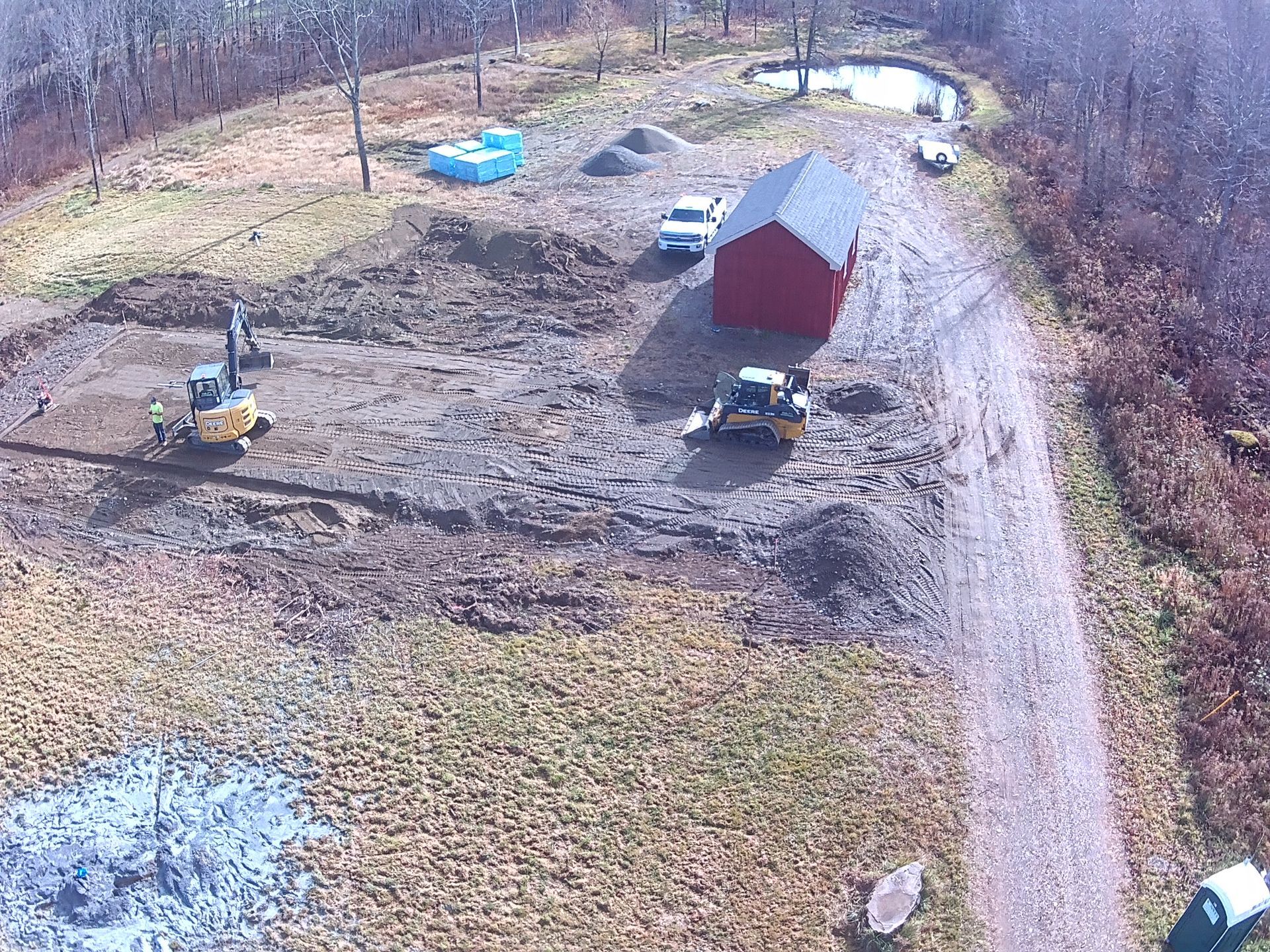 An aerial view of a dirt road leading to a red barn