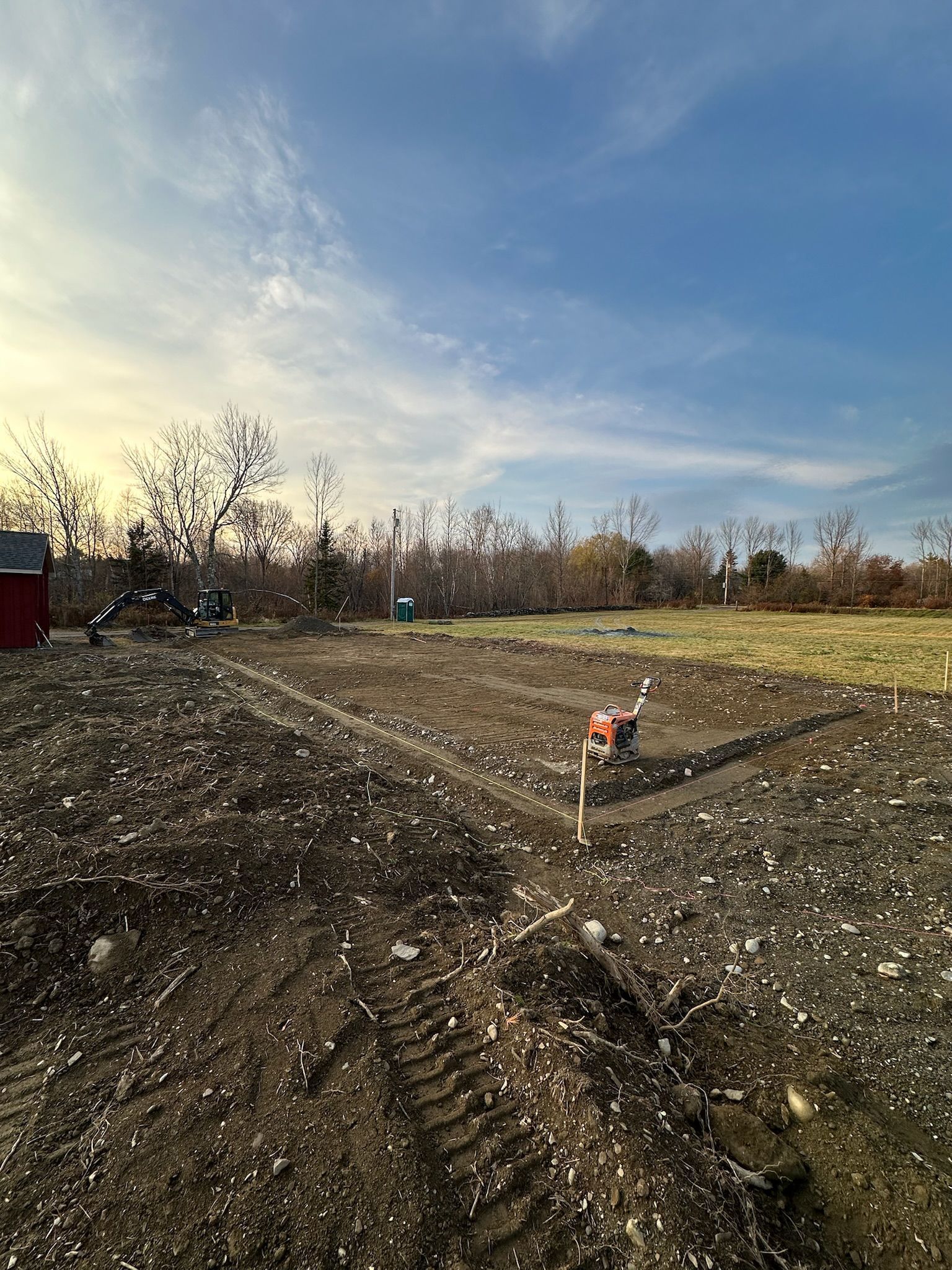 A dirt field with a red shed in the background.