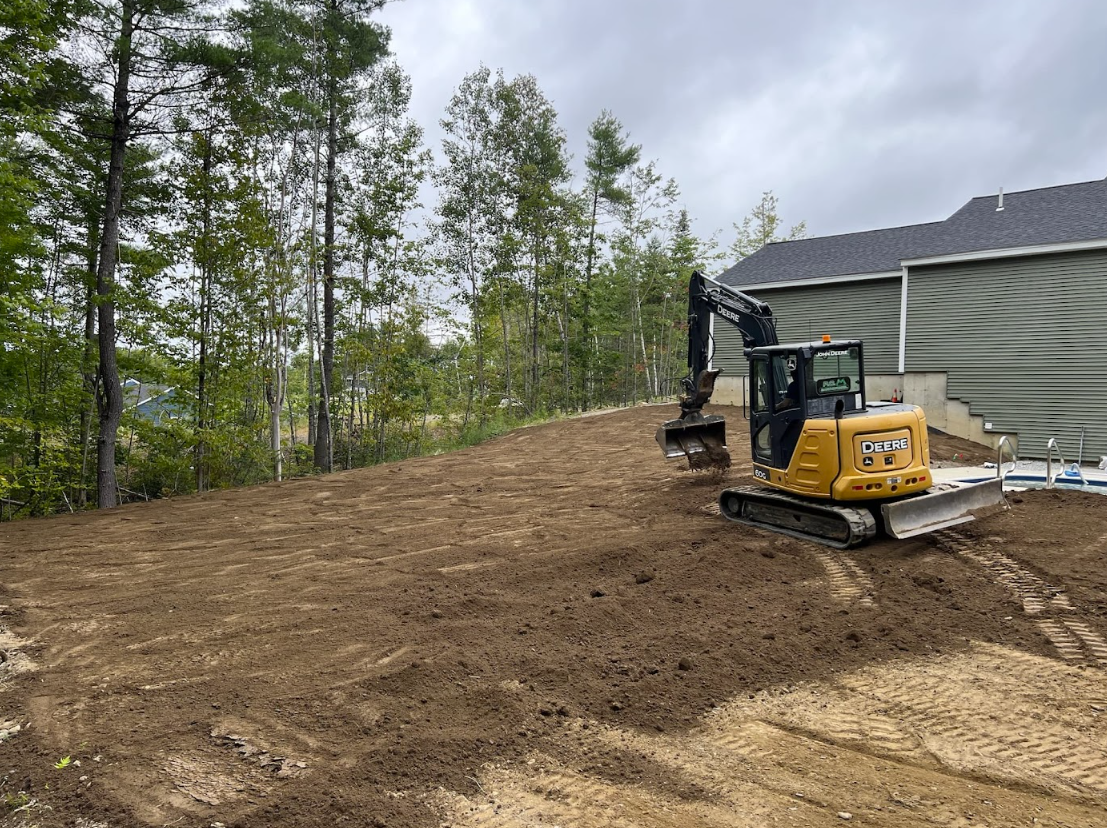 A bulldozer is moving dirt in a field in front of a house.