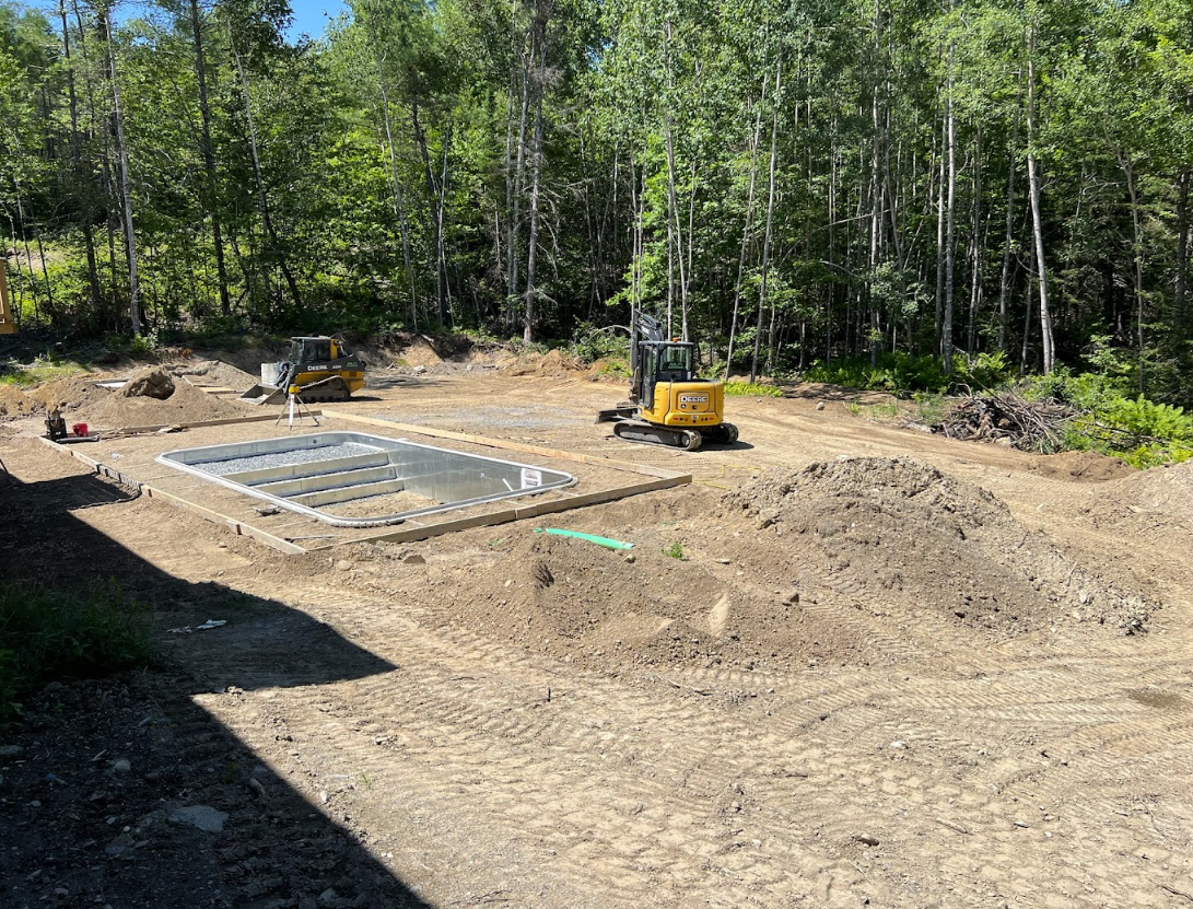 A construction site with a lot of dirt and trees in the background.