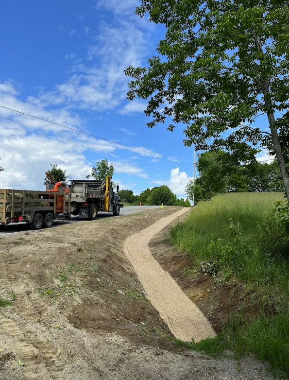 A dump truck is parked on the side of a dirt road.