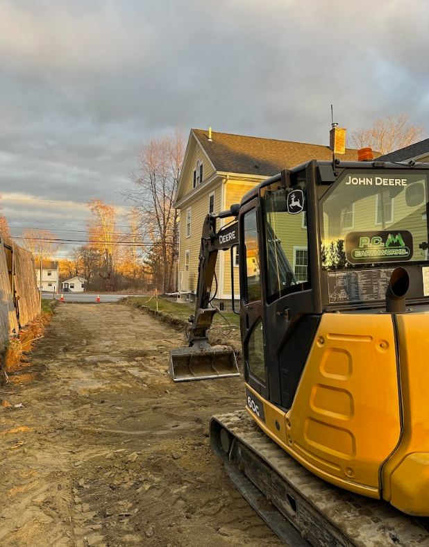 A yellow and black excavator is parked in front of a house.