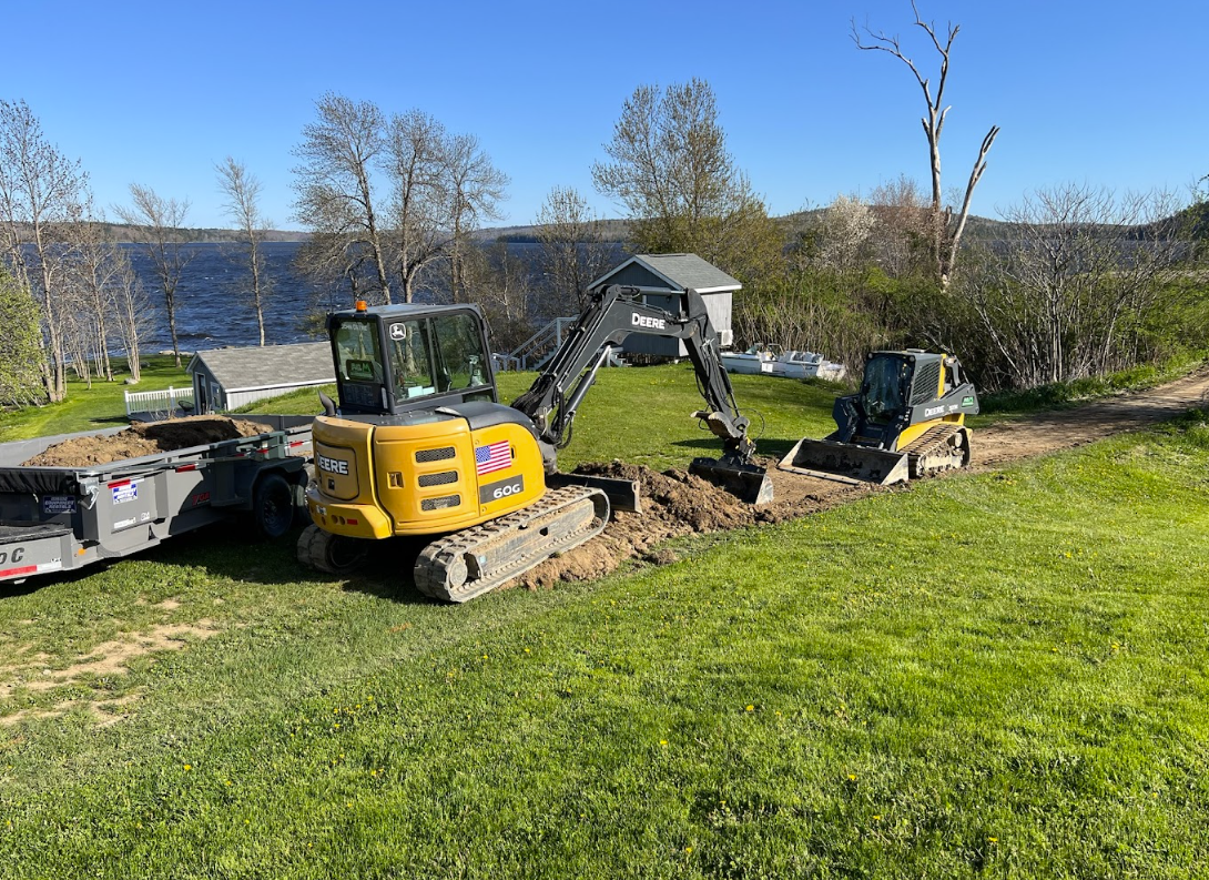 A couple of excavators are sitting on top of a lush green field.