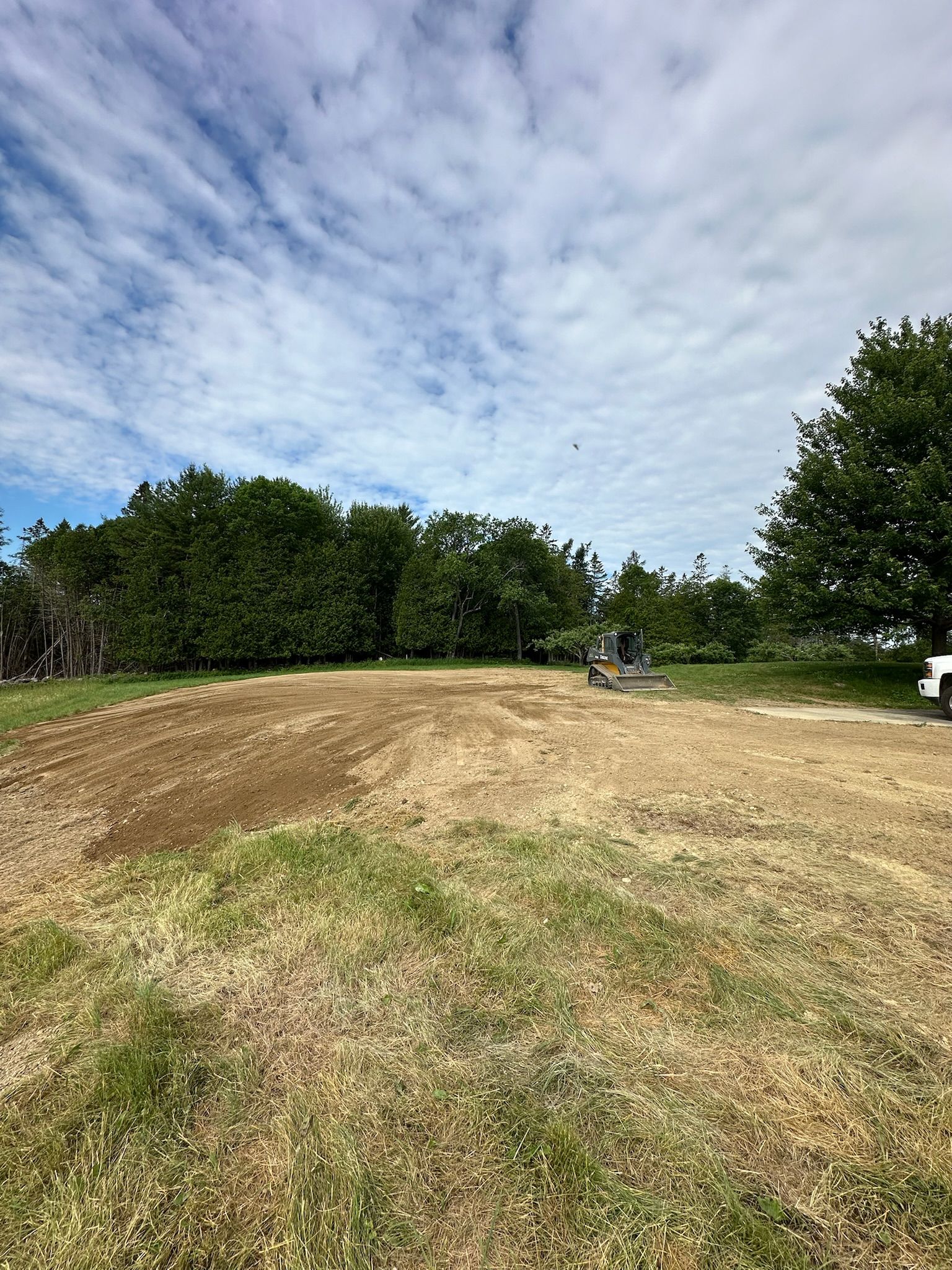 There is a house in the background and a lot of dirt in the foreground.