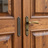 Close-up of wooden double doors with a brass handle and dark metal pull plates.