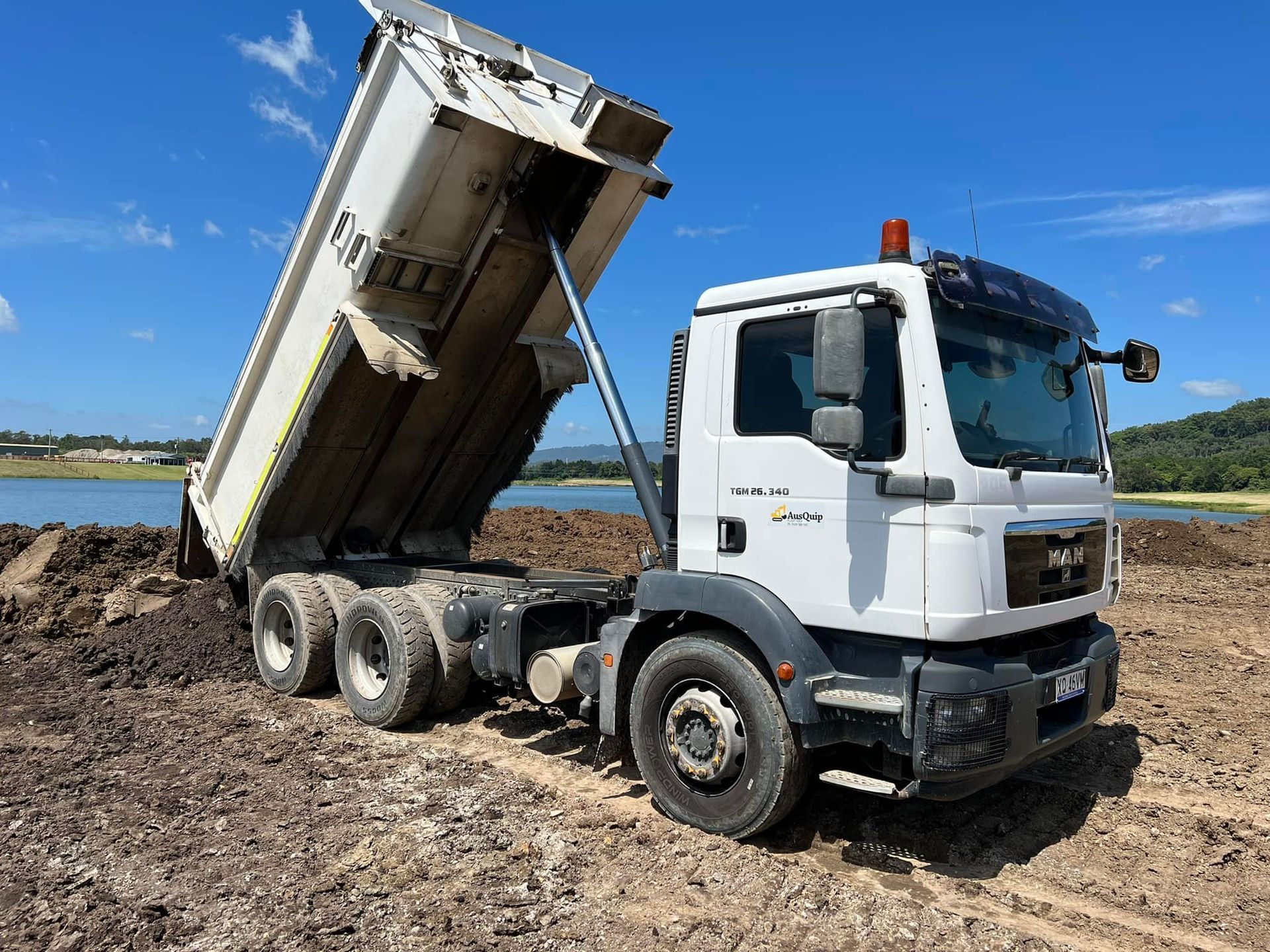A large orange excavator is sitting on top of a pile of dirt.
