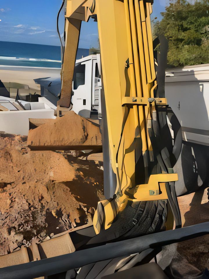 A yellow excavator is loading dirt into a truck