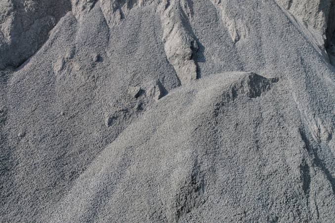 A pile of gravel is sitting on top of a pile of sand.