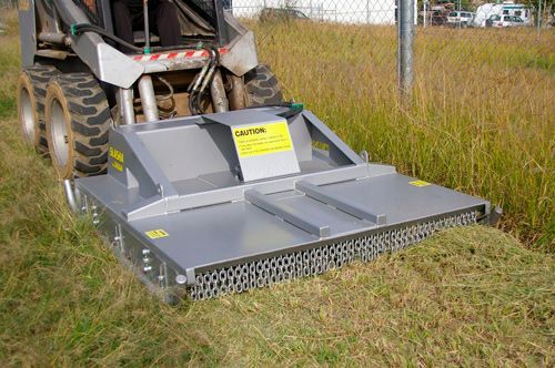 A small tractor is cutting grass in a field.
