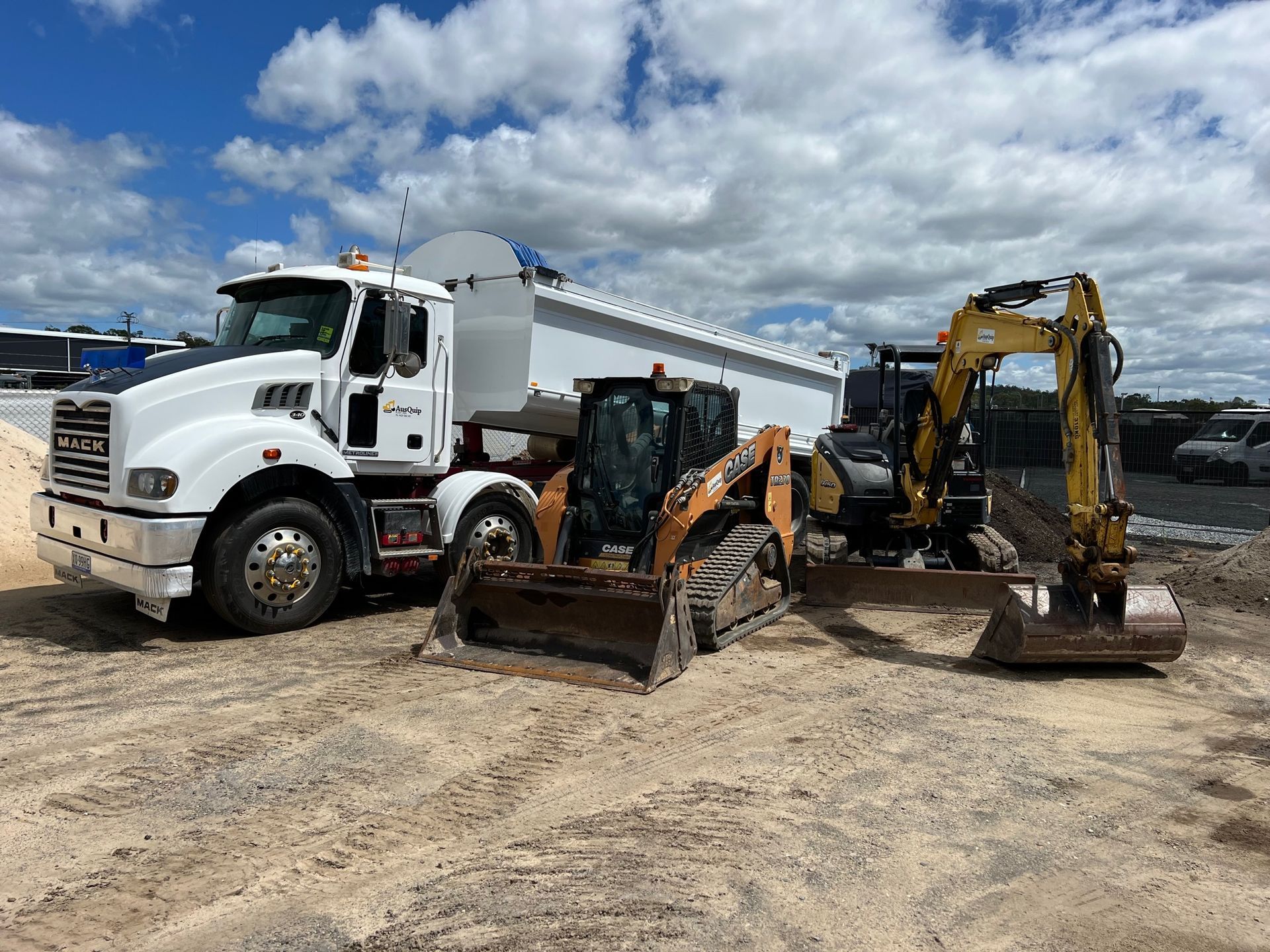 A dump truck and a bulldozer are parked next to each other in a dirt lot.