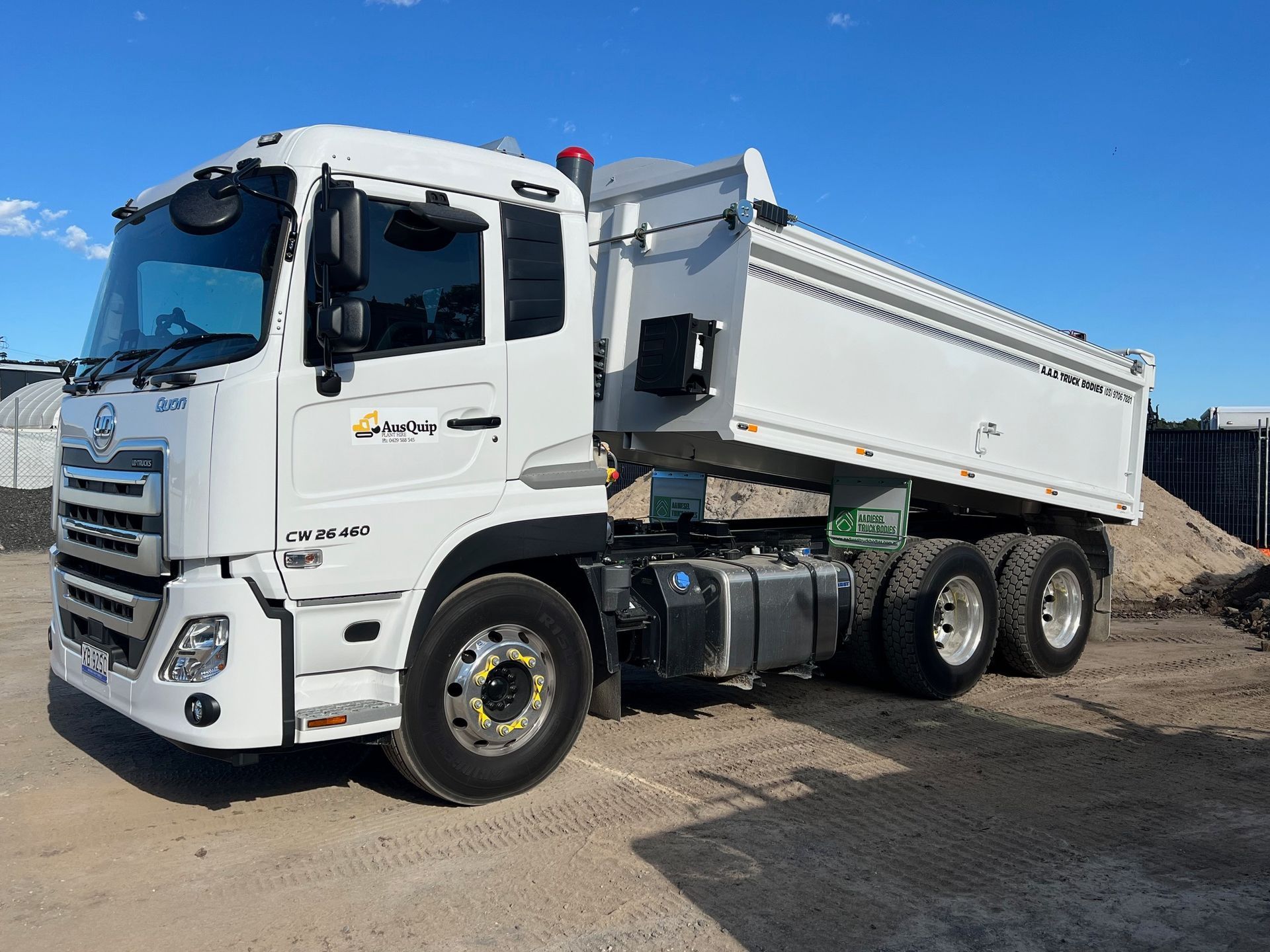 A white dump truck is parked in a dirt lot.