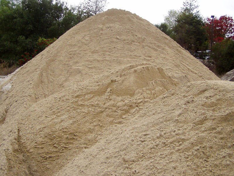 A pile of sand with trees in the background
