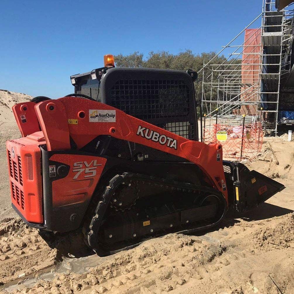 A kubota skid steer is parked in the dirt on a construction site.