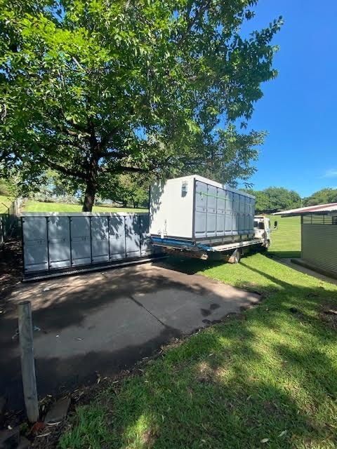A Portable Bathroom Trailer is Parked in a Driveway Next to a Tree — Ecotreat Solutions NT in Darwin City, NT