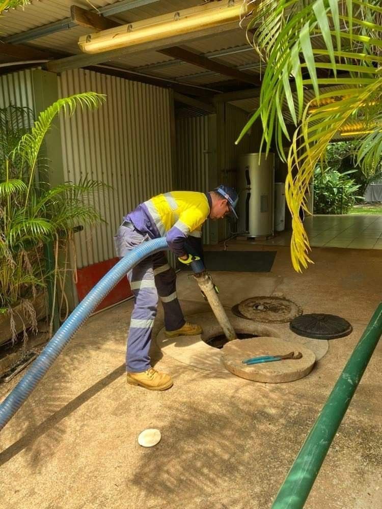 Man is Pumping Water into a Manhole Cover with a Hose — Portable Toilets in Winnellie, NT
