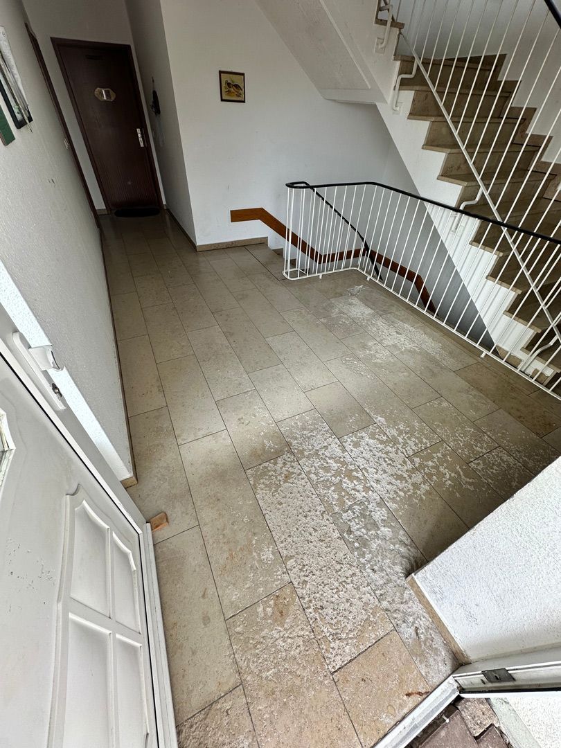 Flur mit gefliestem Boden, Treppe und Tür.