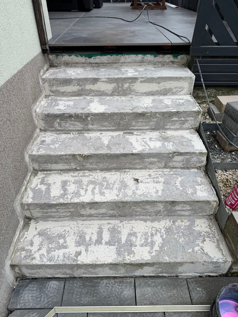 Betonstufen führen zu einem Türrahmen mit verwitterten grauen Oberflächen.