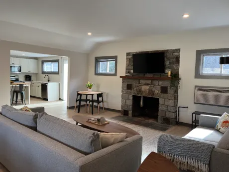 Modern living room with stone fireplace, sectional sofa, TV, and open kitchen view