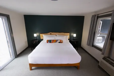 Bedroom with a king bed, dark green accent wall, and windows on both sides