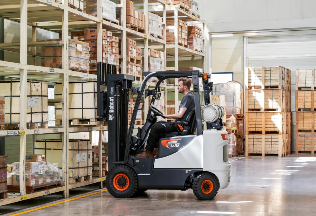 Forklift operator in a warehouse, picking up inventory from shelves.