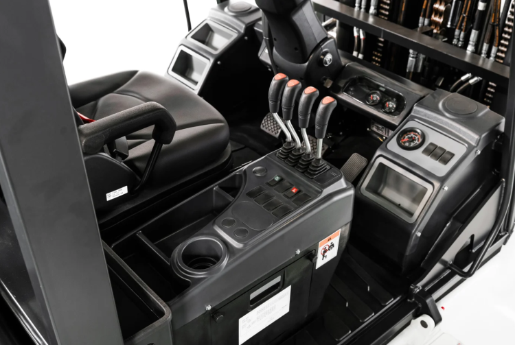 Forklift interior with black seat, levers, control panel, and cup holder.