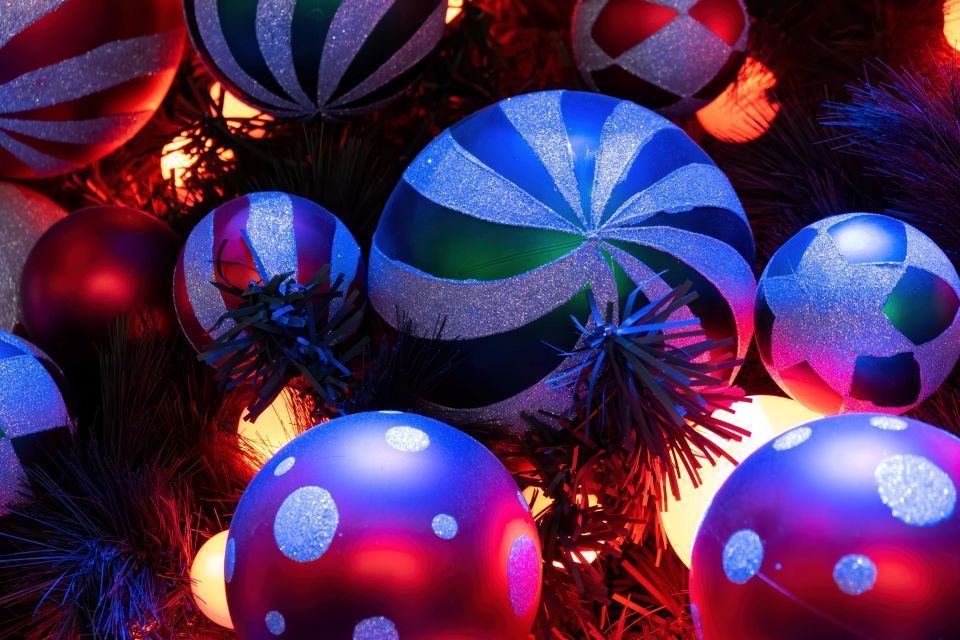 Christmas ornaments, various colors, patterns, and sizes, on a Christmas tree, glowing lights.
