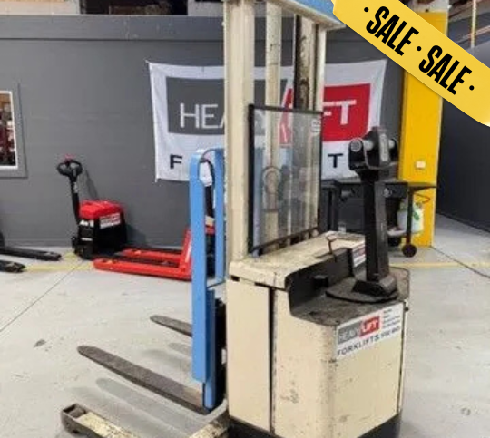 Forklift with extended forks, inside a warehouse. 