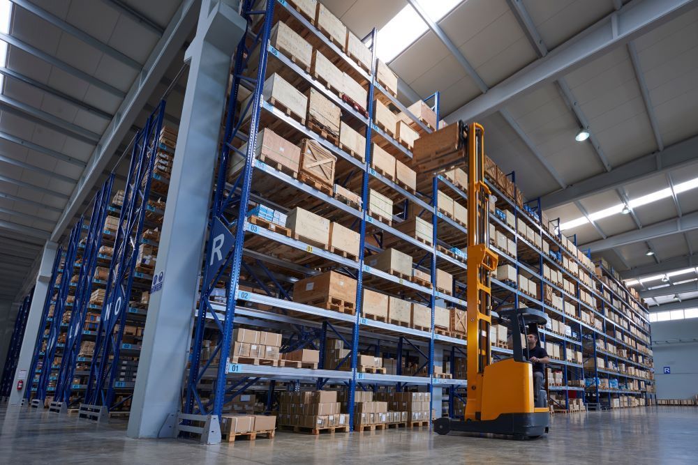 a high-reach forklift is driving through a large warehouse filled with shelves 