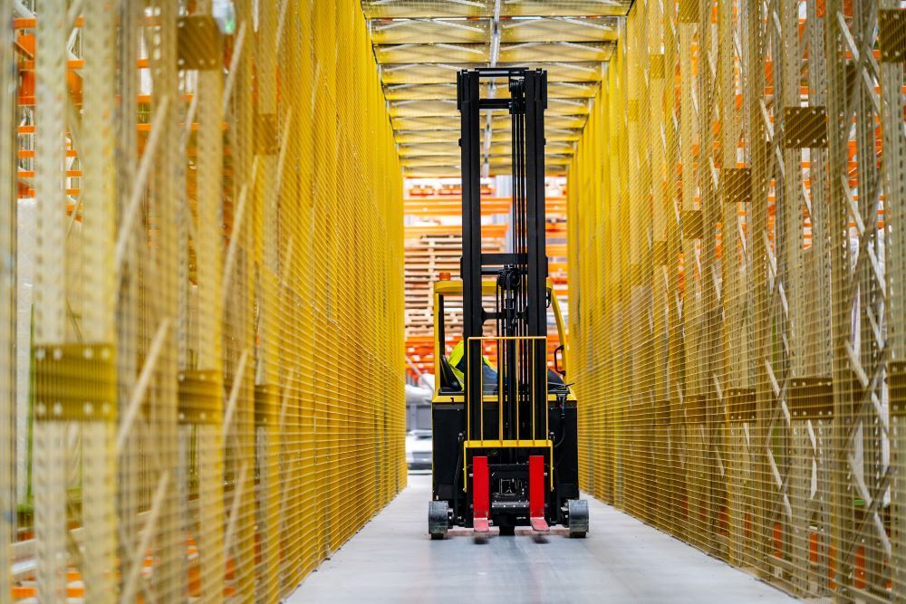 a high-reach forklift is driving through a warehouse filled with lots of shelves 