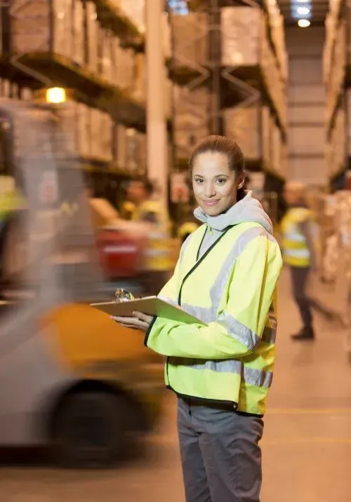 a woman is standing in a warehouse holding a clipboard  forklift hire dandenong