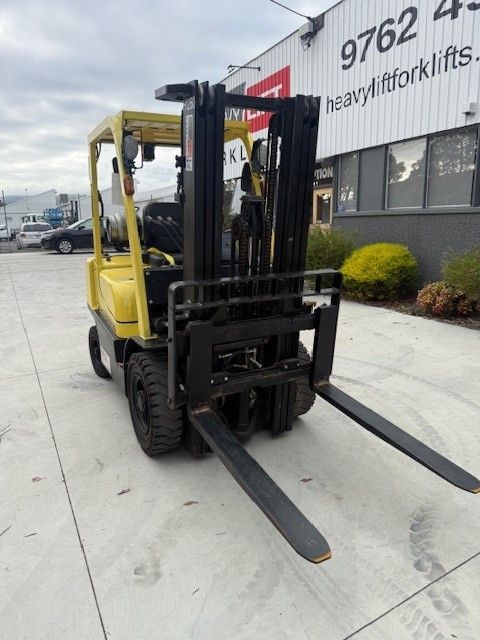 A yellow hyster 2.5T forklift for sale  parked in front of a building that says heavyliftforklifts