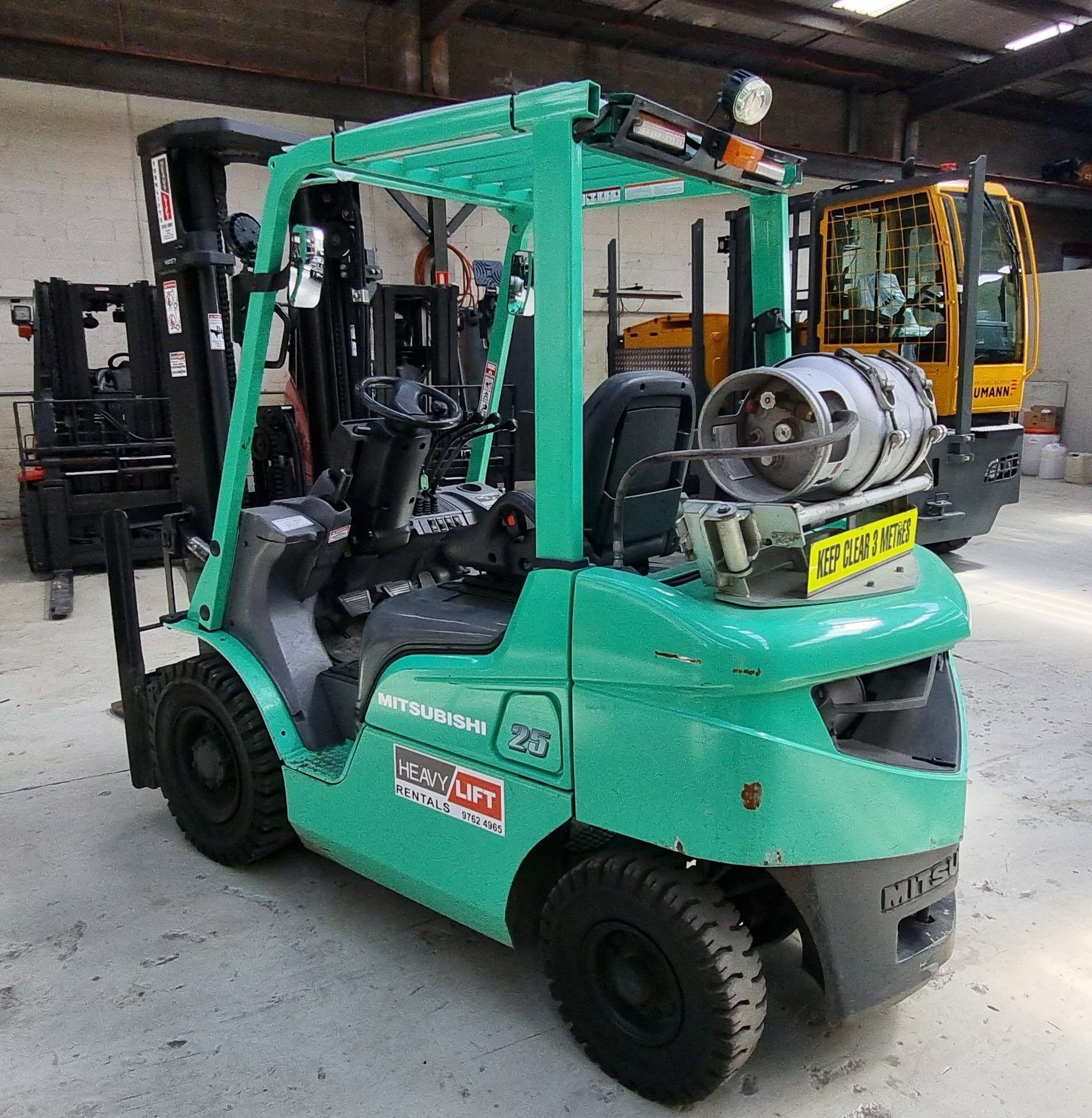 A green forklift is parked in a warehouse