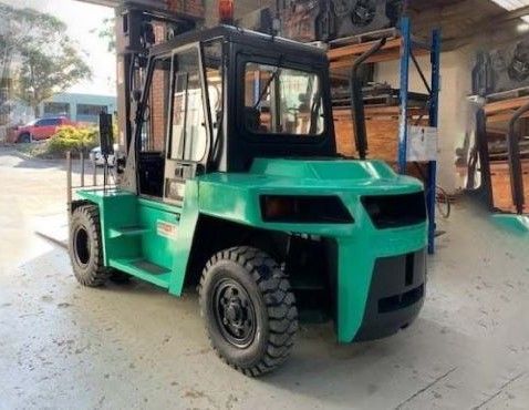 A green forklift is parked at Heavy Lift Forklifts Melbourne's warehouse