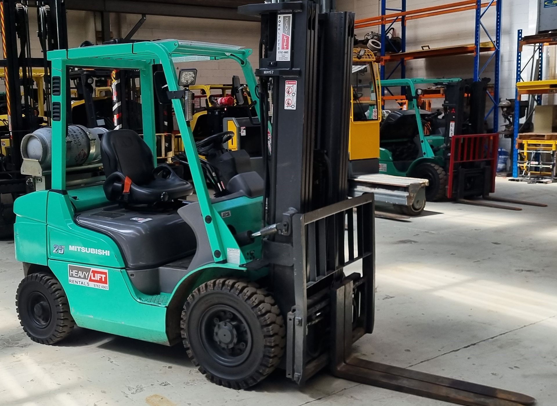 A green forklift is parked in a warehouse