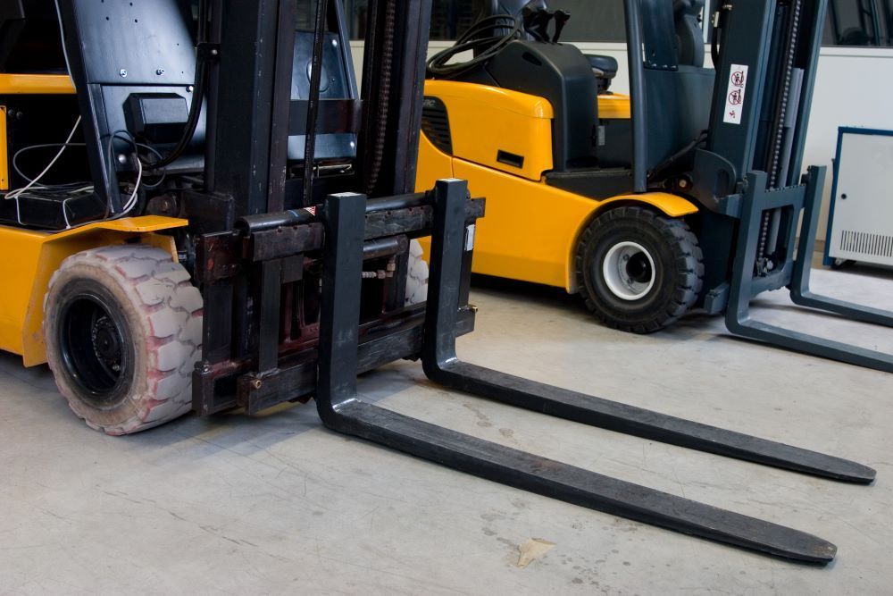 two counterbalance forklifts parked next to each other in a warehouse 