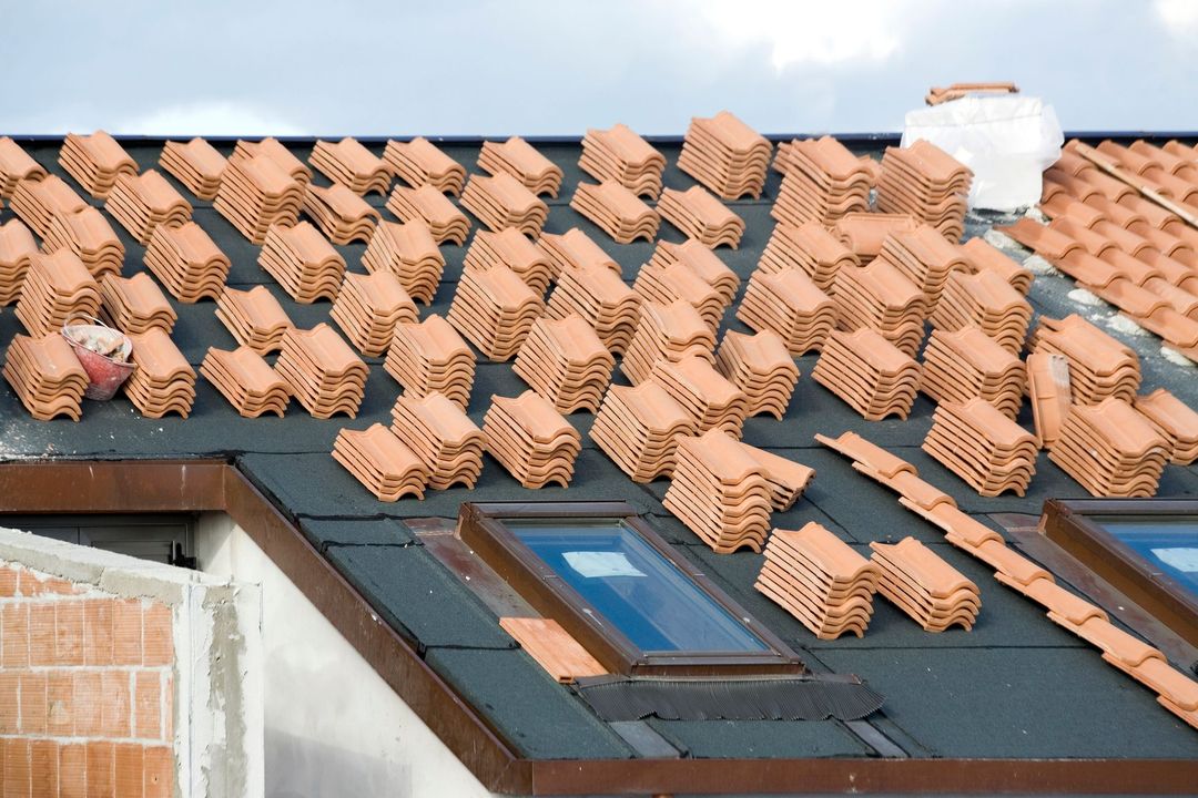Tetto in costruzione con pile di tegole in terracotta.