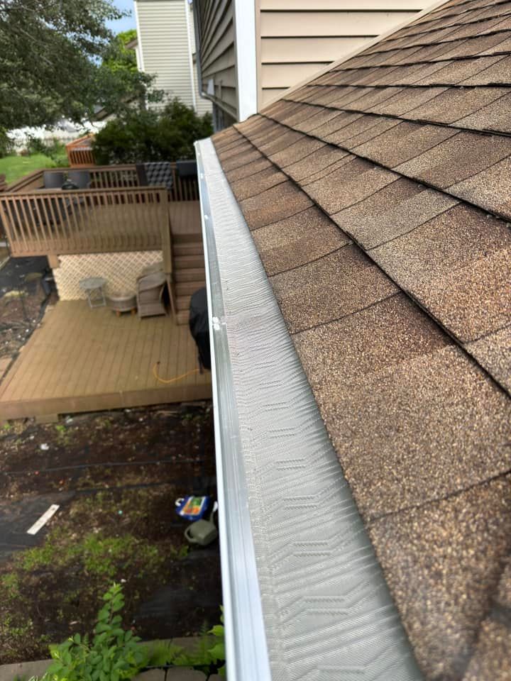Brown shingle roof with a gutter guard, overlooking a wooden deck and yard.