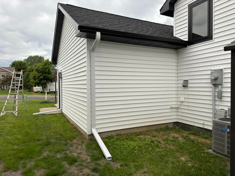 White house exterior with black roof and gutters, featuring vinyl siding.