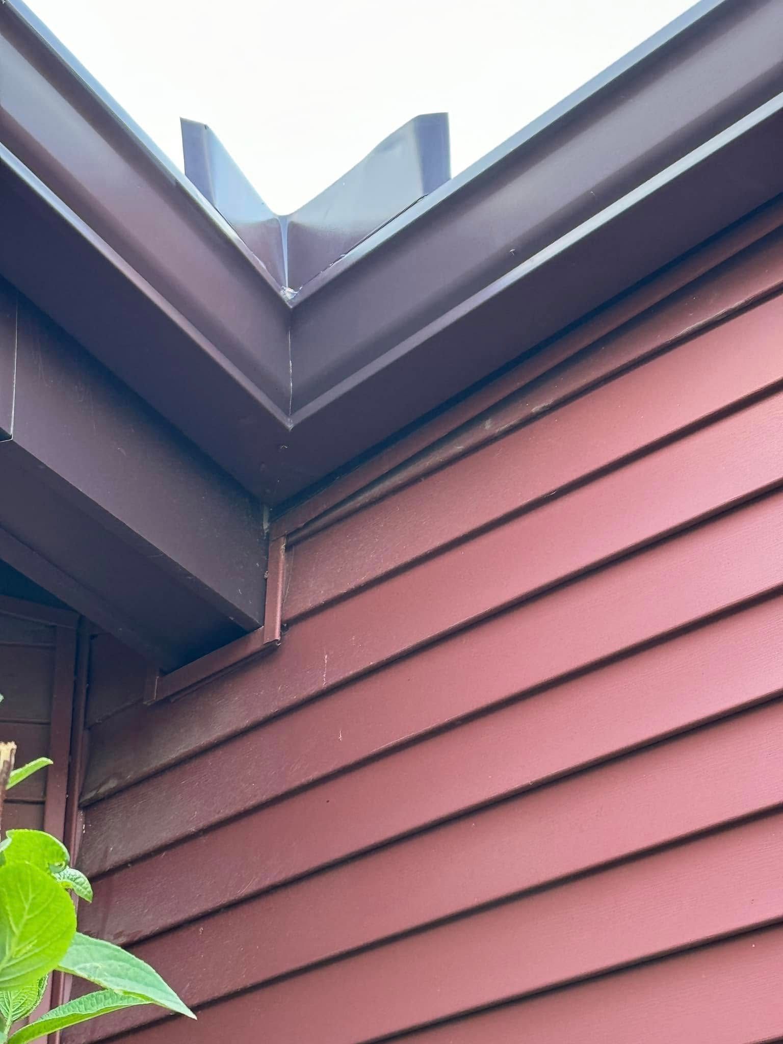 Brown painted eaves and siding on a corner of a building, seen from below.