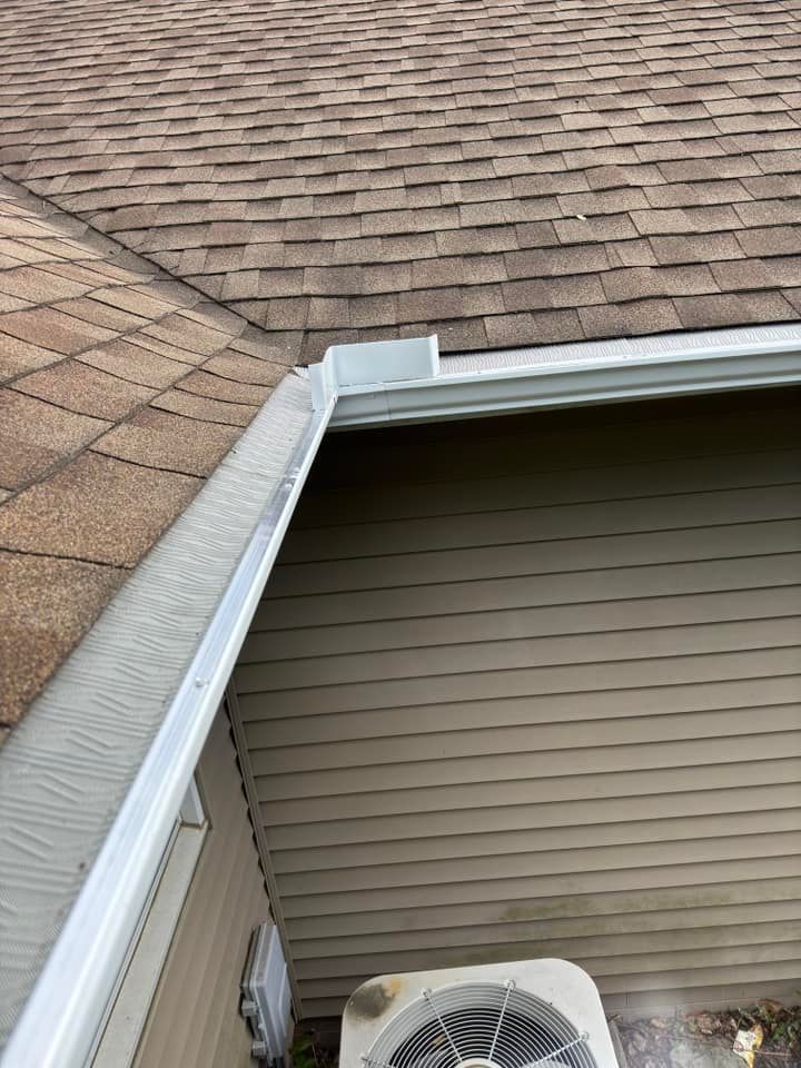 Overhead view of a house's roof, gutter, and siding, with an air conditioning unit below.