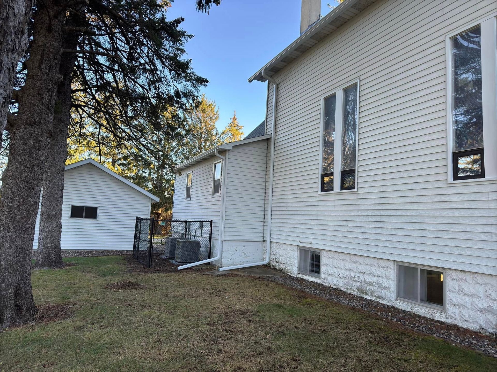 White buildings with tall windows and a small shed on a grassy lawn.