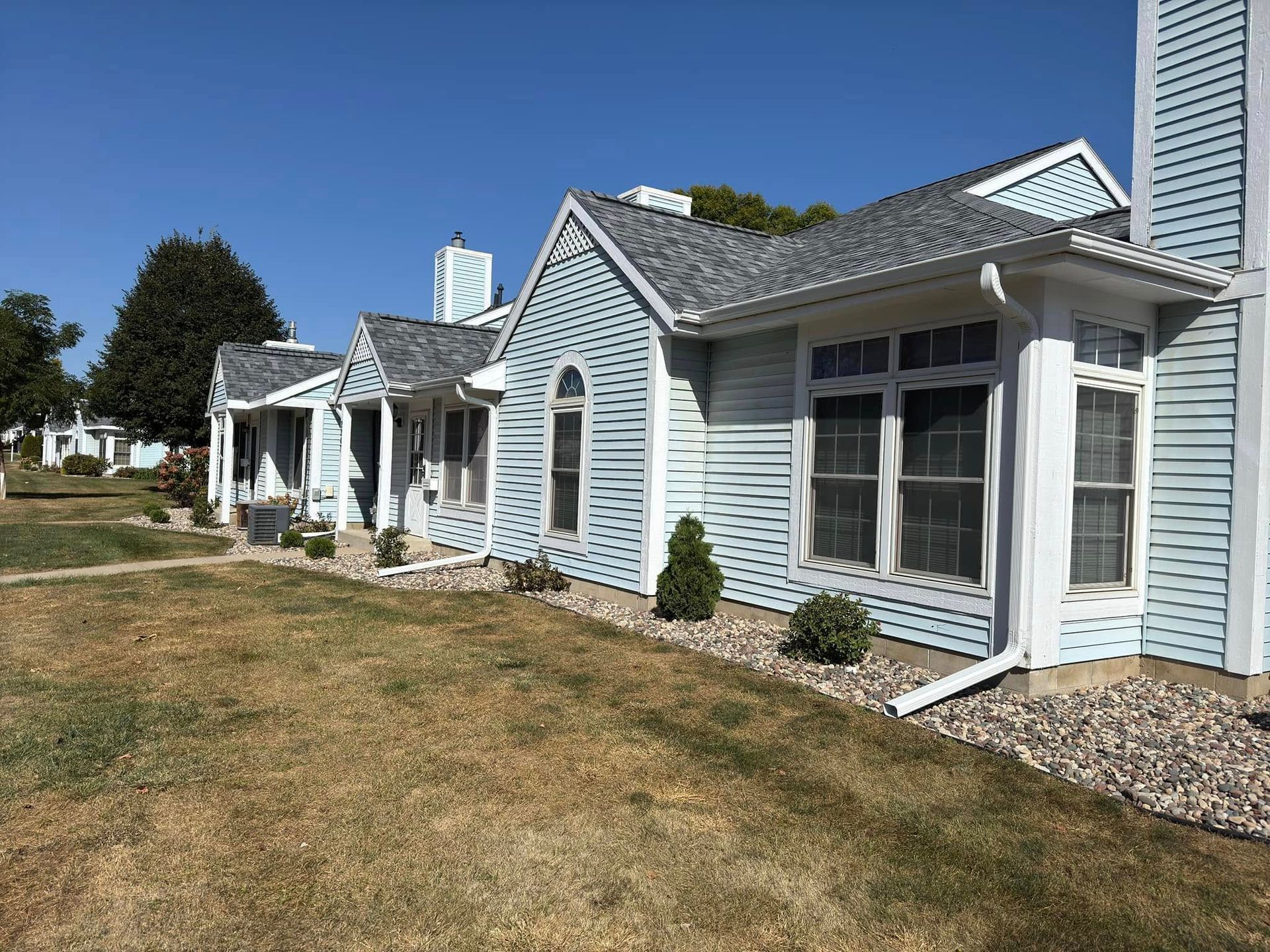 Light blue houses with gray roofs and white trim on a sunny day.