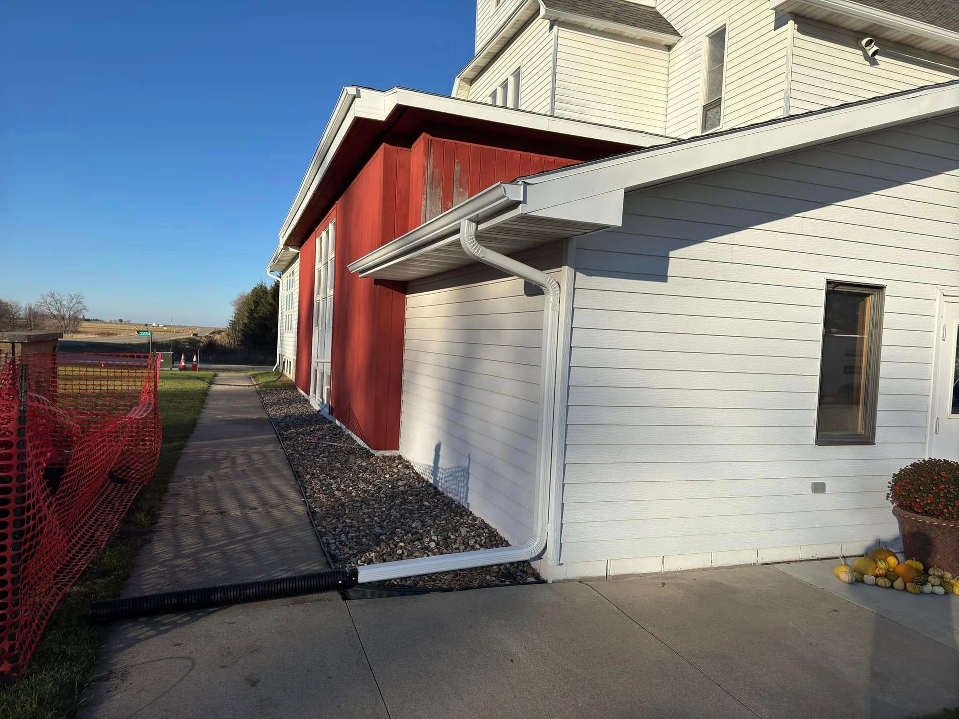 Red and white buildings with a brick pathway and a red safety fence, under a blue sky.