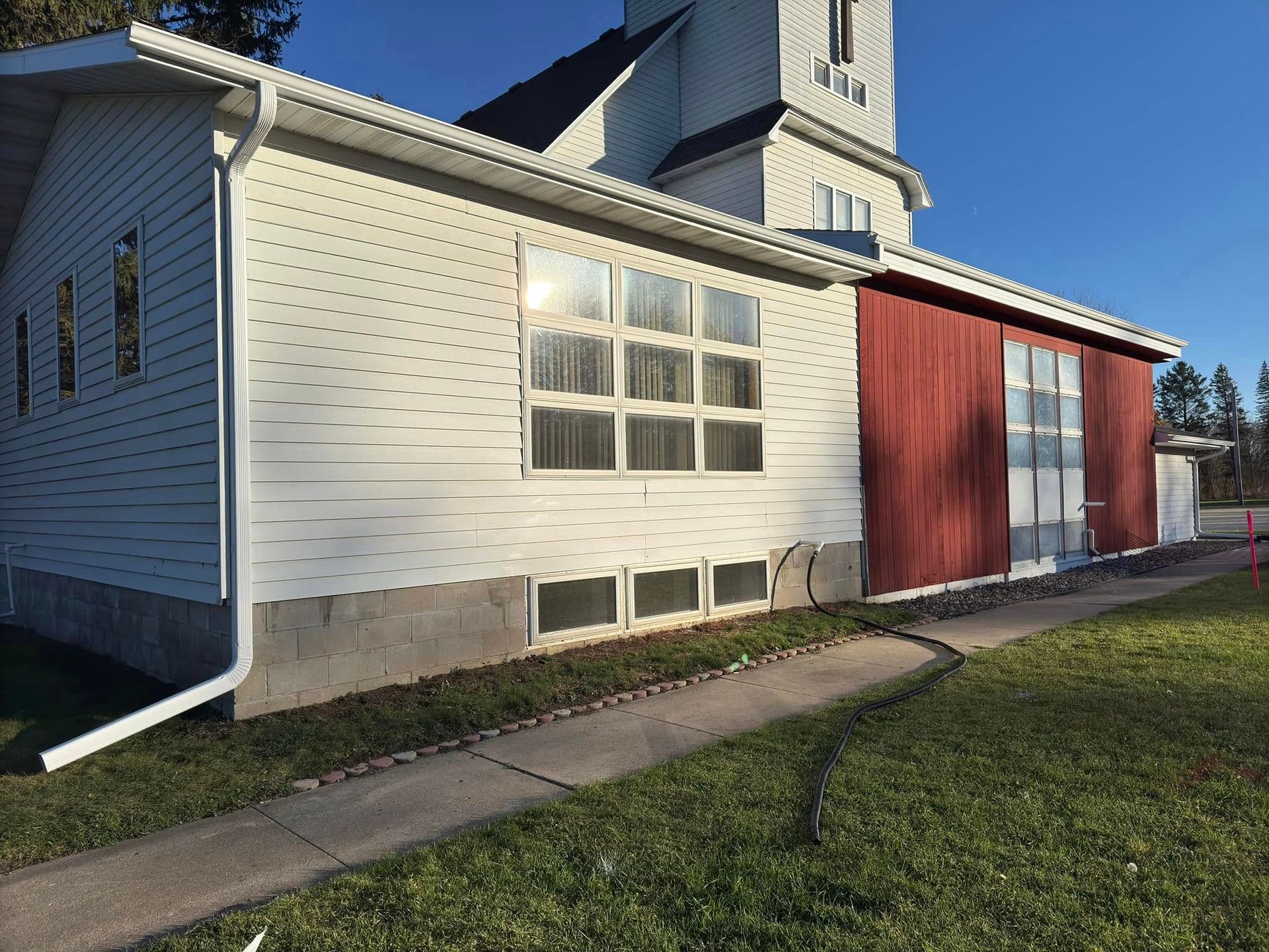 White and red church building with a pathway on a grassy lawn.