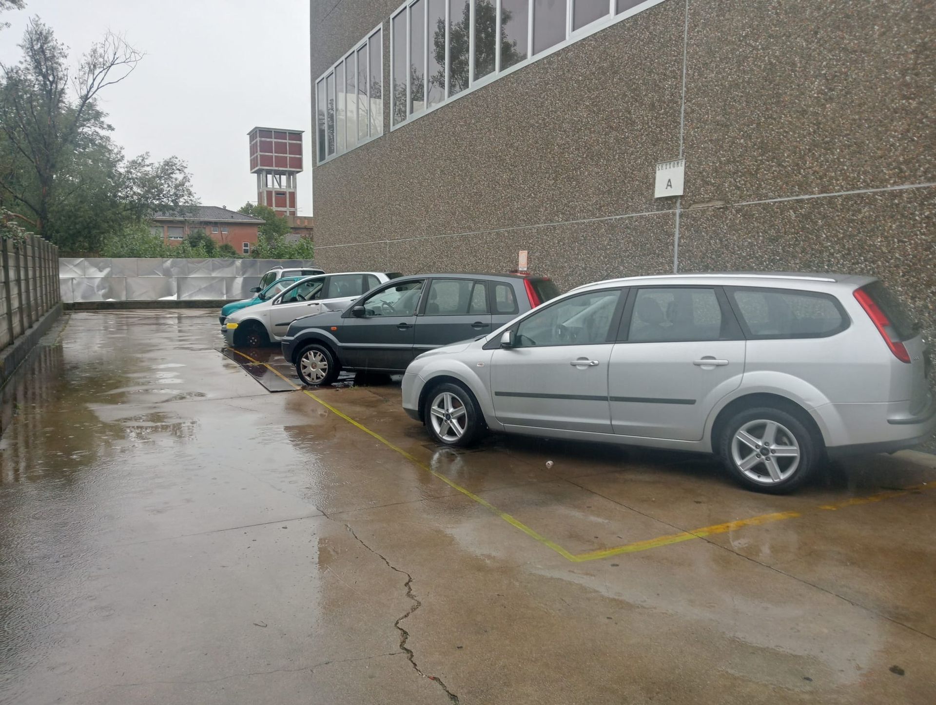 Una fila di auto è parcheggiata in un parcheggio in una giornata piovosa