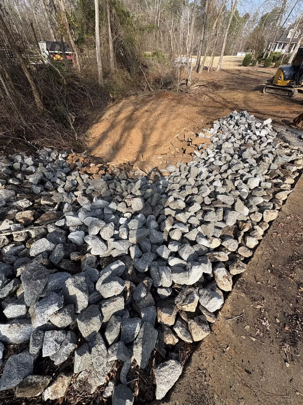 Rocks lining a ditch to prevent erosion. Sunny outdoors.
